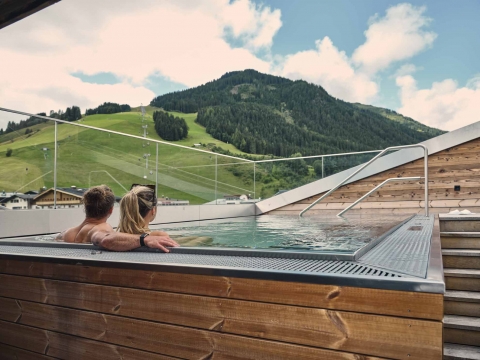 Zwei Personen im Rooftop-Whirlpool schauen in die Landschaft