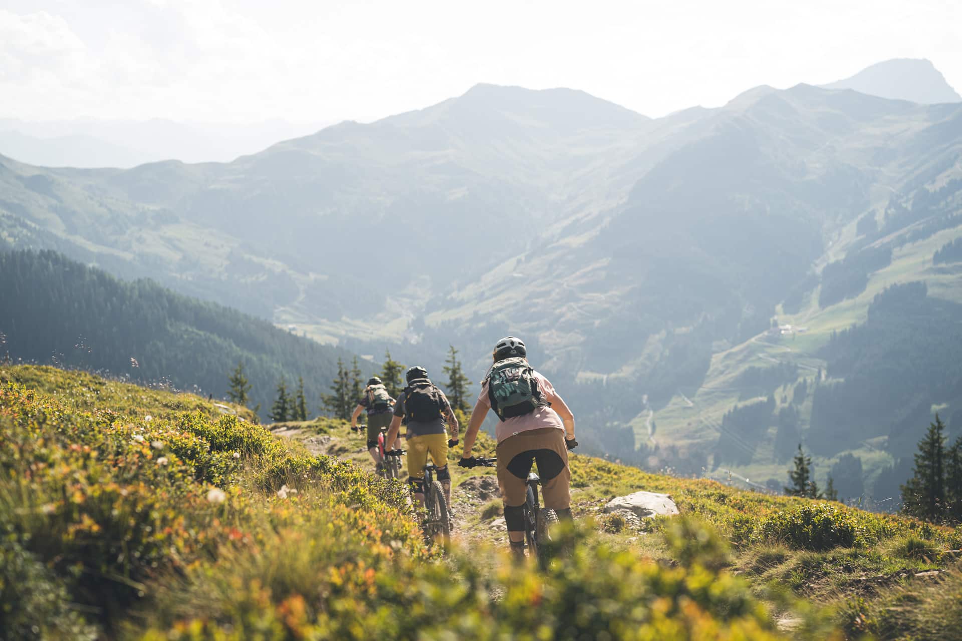 3 Personen am E-Bike fahren den Berg hinunter